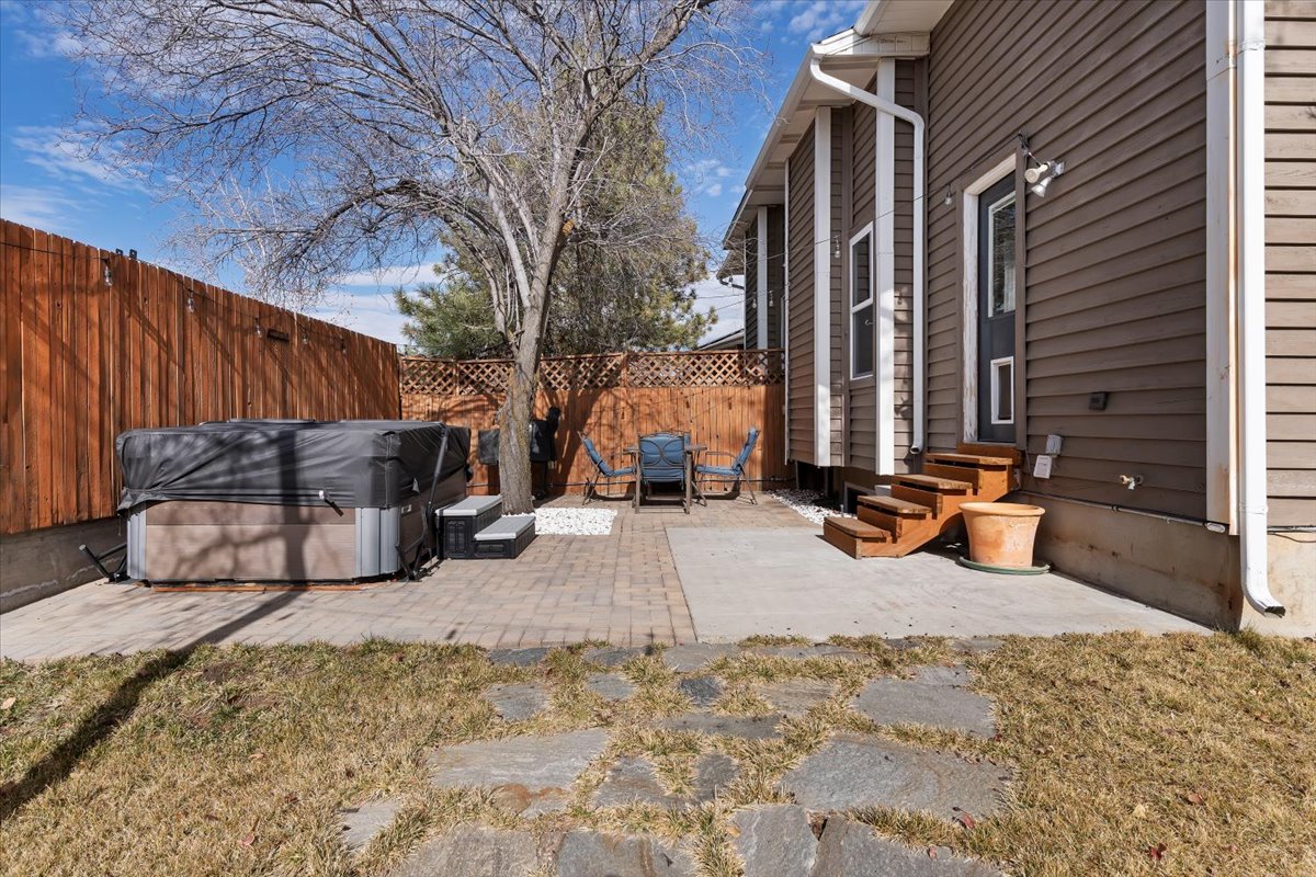 Rear exterior featuring wood-finish siding, a private wood fence, a paver patio, a concrete patio, and natural stone stepping pavers