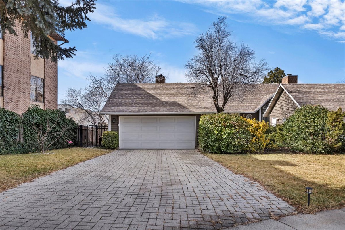 Shingled exterior with a prominent attached garage and a paver driveway