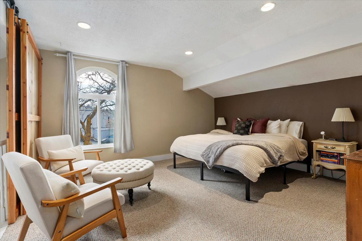 Carpeted bedroom with an arched window, recessed lighting, and a barn door entry