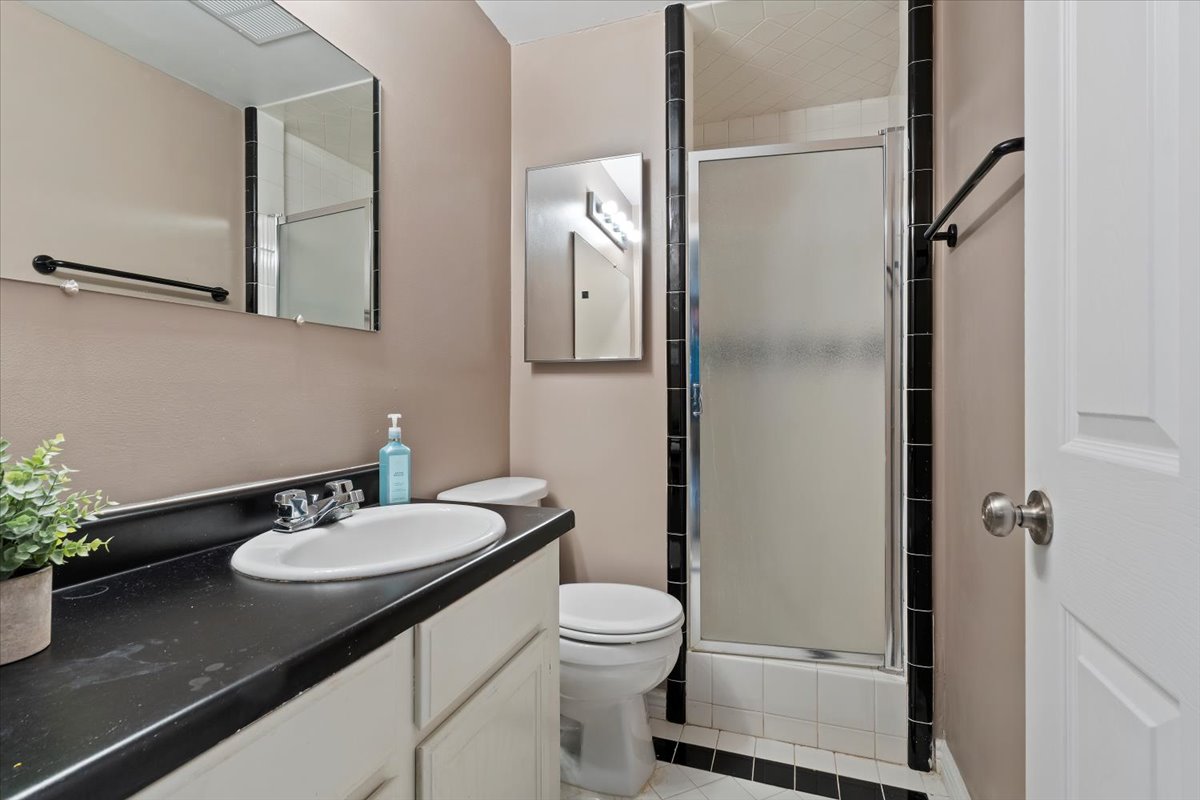 Bathroom featuring a vanity with an integrated sink, a dark countertop, and white cabinetry