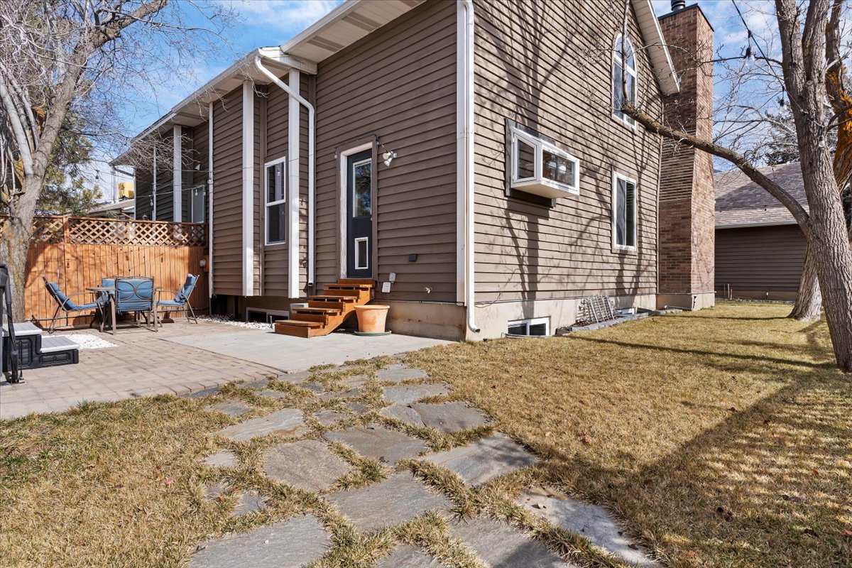 Rear exterior featuring brown horizontal siding, a visible brick chimney, and white-framed windows