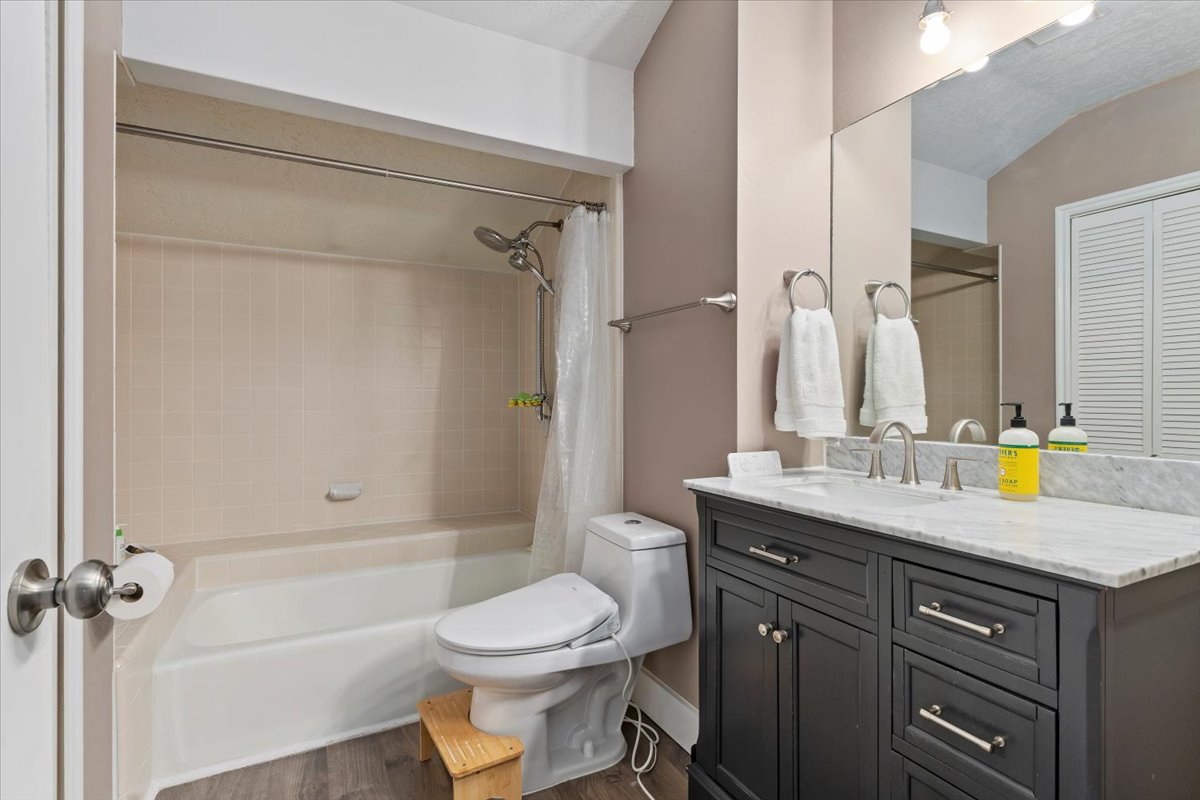 Bathroom featuring a single vanity with a marble countertop, white undermount sink, and brushed nickel hardware