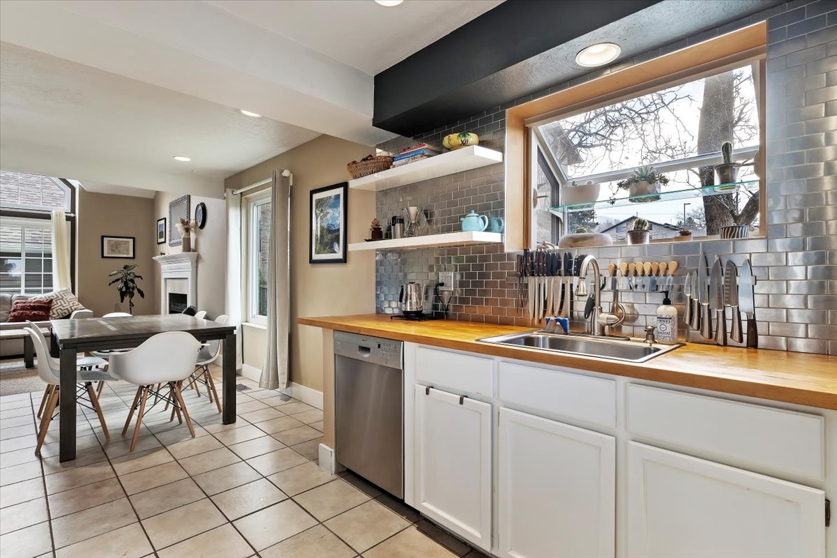 Kitchen featuring a stainless steel undermount sink, wood-finish countertops, white cabinetry, and stainless steel appliances