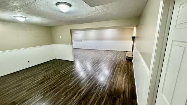 Open-concept room featuring wood-finish flooring, white wainscoting, and recessed lighting
