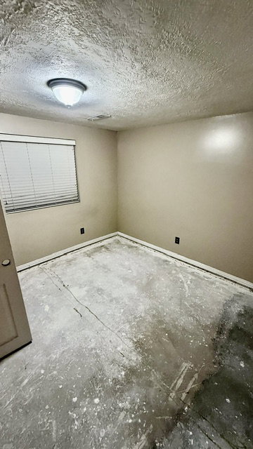 Bedroom featuring neutral wall paint, a ceiling-mounted light fixture, and a window with blinds