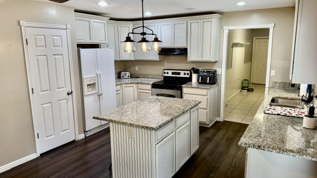 Kitchen featuring white cabinetry, granite countertops, a central island, dark wood-finish flooring, and recessed lighting