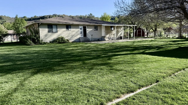 Expansive green lawn bordering a single-story residence with light-colored siding