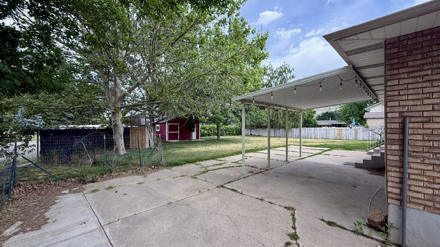 Expansive paved patio area featuring an attached carport with string lighting
