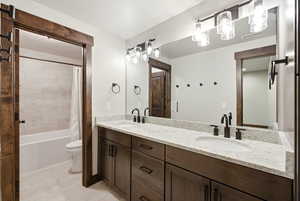 Bathroom featuring a dual vanity with dark wood cabinetry, light speckled countertops, and undermount sinks