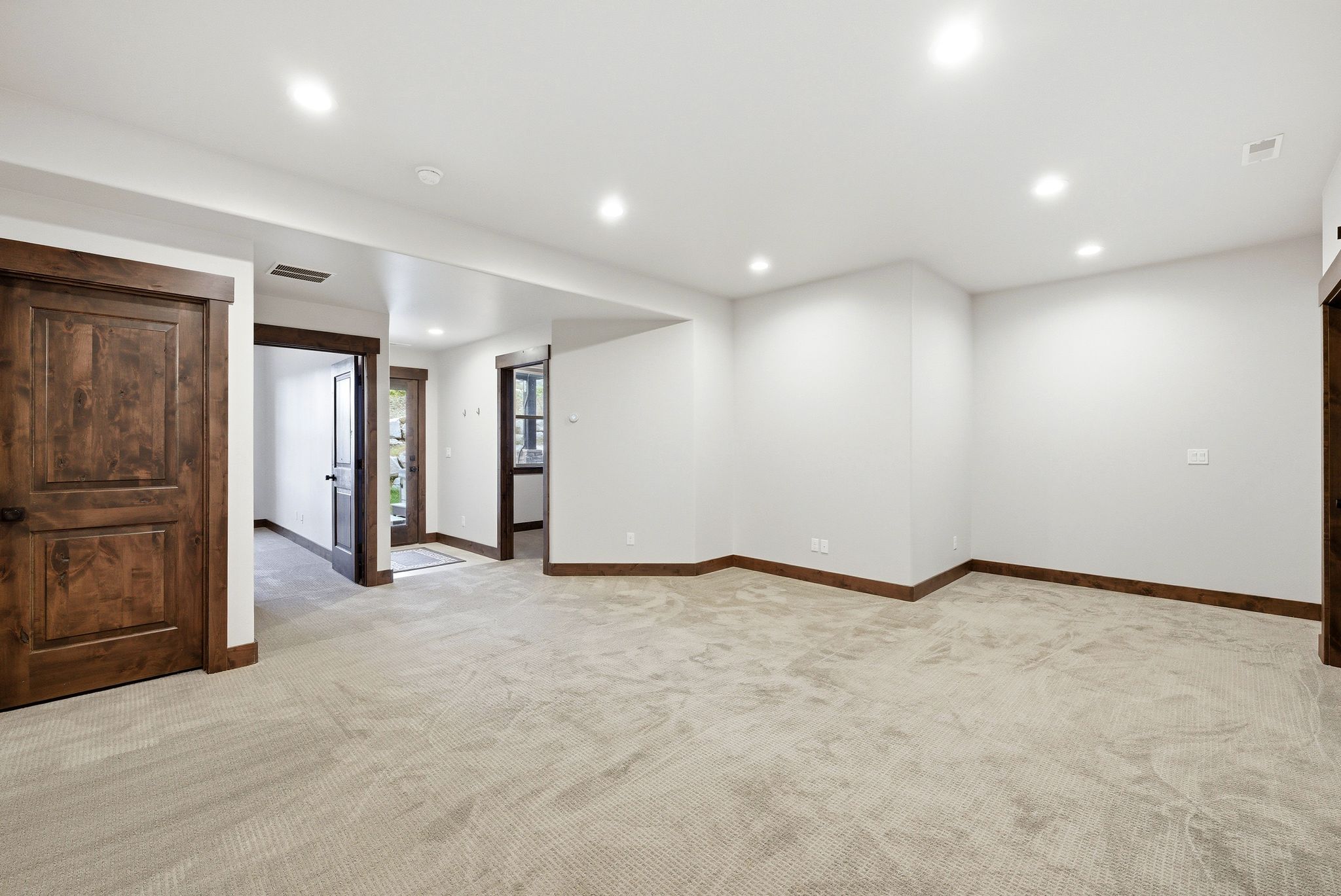 Spacious interior room featuring light-toned carpet flooring, recessed ceiling lighting, and crisp white walls