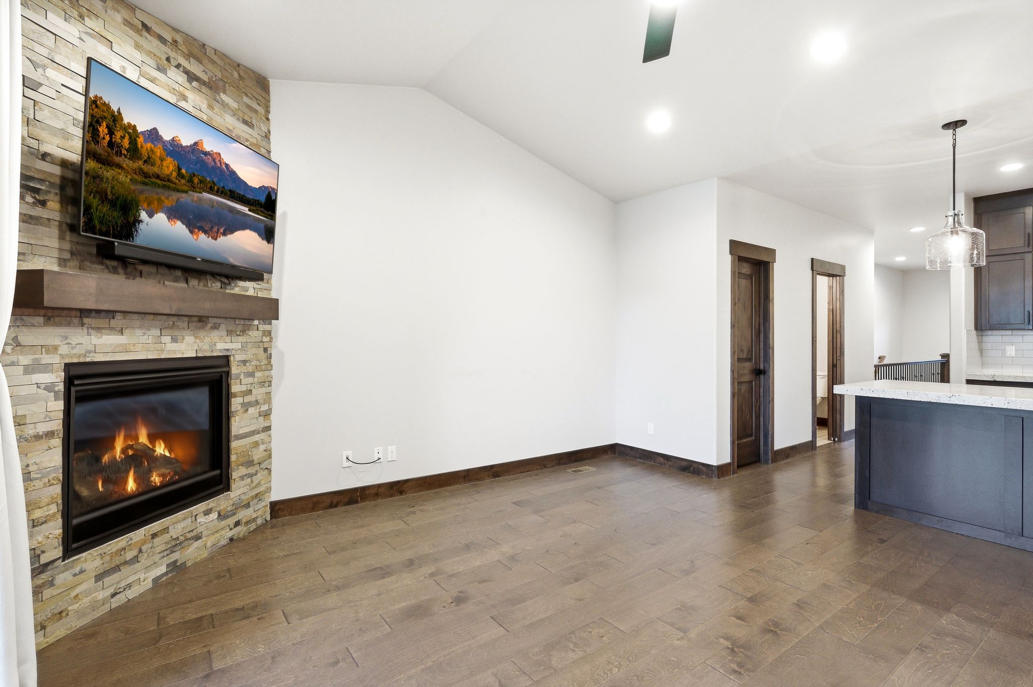 Living space featuring a stone-clad fireplace with a wood mantel, wood-finish flooring, and recessed lighting