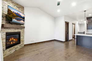 Living space featuring a stone-clad fireplace with a wood mantel, wood-finish flooring, and recessed lighting