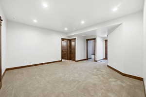 Spacious carpeted room featuring recessed lighting, white walls, and dark wood-finish trim and doors