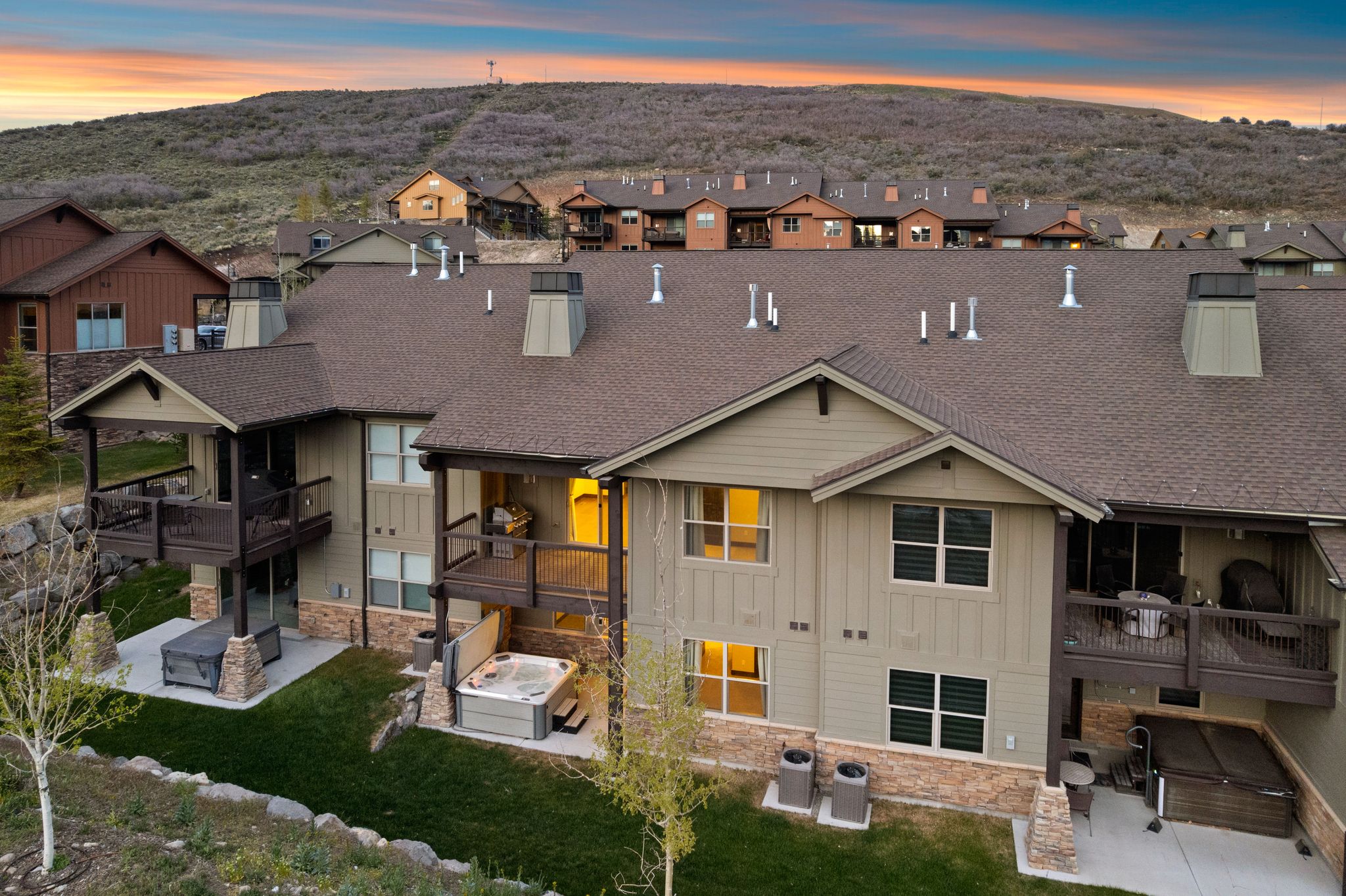 Rear exterior featuring multiple decks, ground-level patios, and dual hot tubs