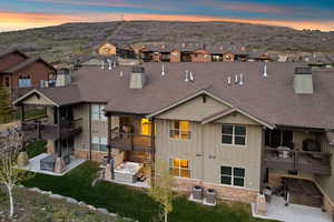 Rear exterior featuring multiple decks, ground-level patios, and dual hot tubs
