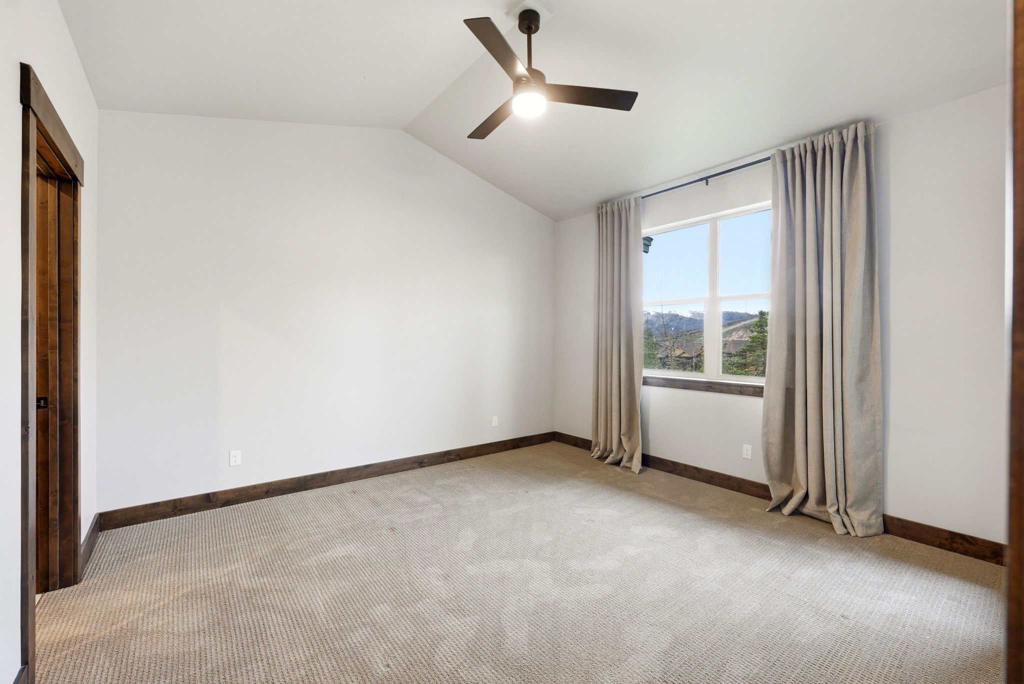 Spacious room featuring vaulted ceilings, a ceiling fan with integrated lighting, and neutral-toned carpeting