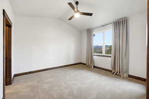 Spacious room featuring vaulted ceilings, a ceiling fan with integrated lighting, and neutral-toned carpeting