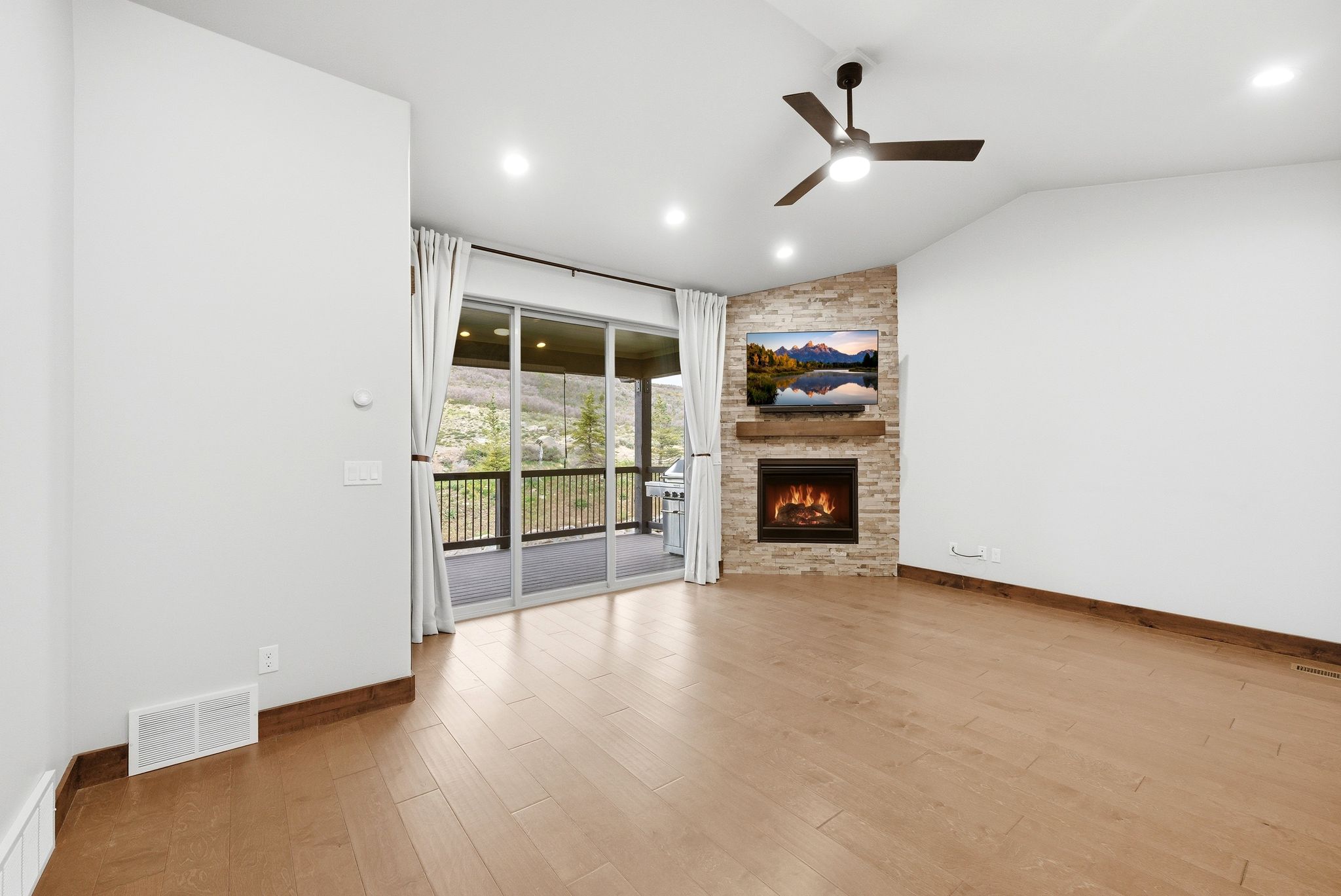 Spacious living area featuring wood-finish flooring, a vaulted ceiling, and recessed lighting