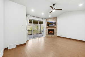 Spacious living area featuring wood-finish flooring, a vaulted ceiling, and recessed lighting