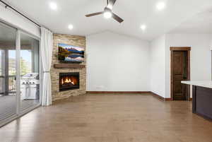 Expansive open-concept room featuring wood-finish flooring, a vaulted ceiling, and recessed lighting