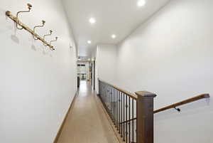 Hallway with wood-finish flooring, recessed ceiling lighting, and a dark wood staircase with wrought iron balusters