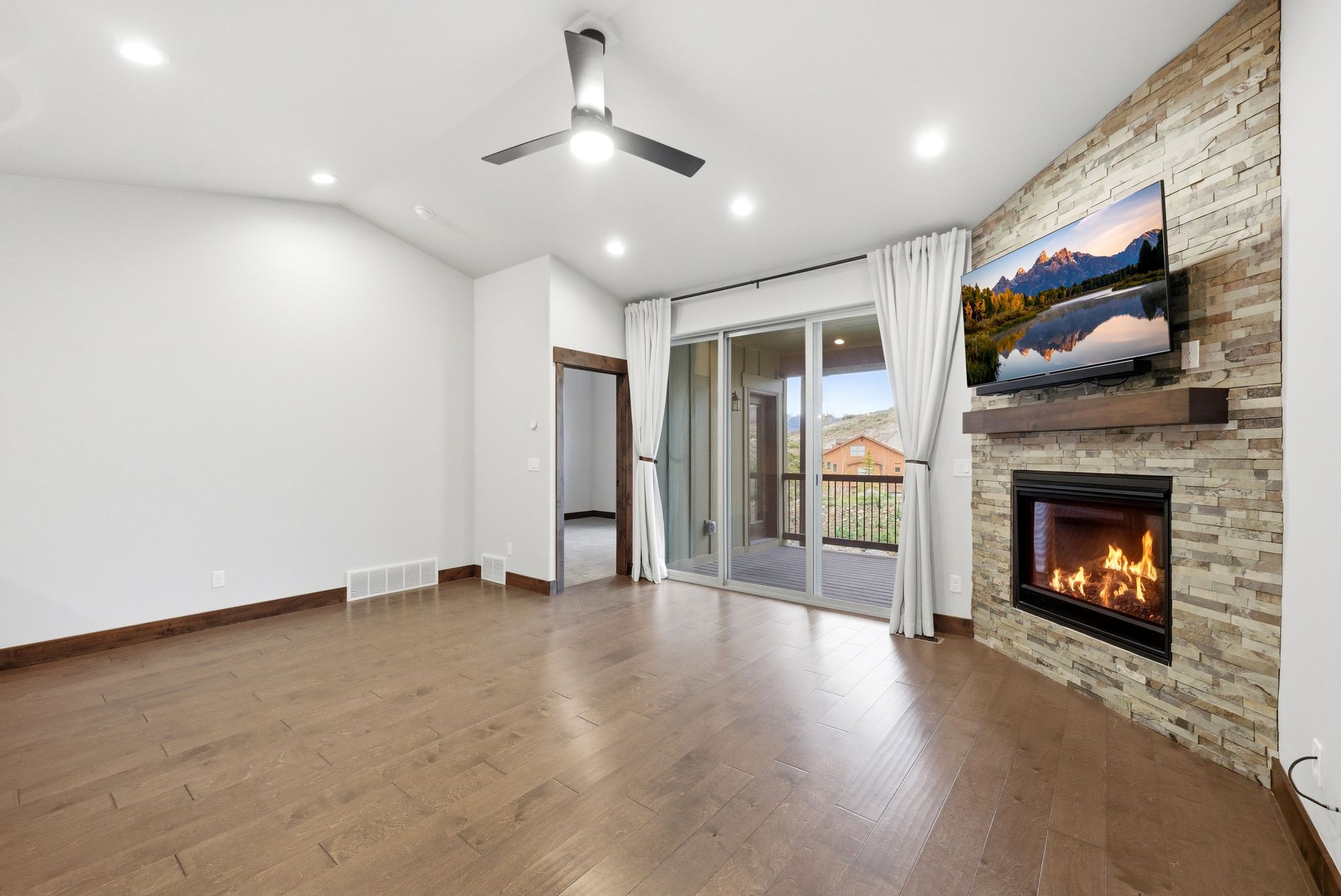Living space featuring a stone-clad fireplace with a wood mantel, wood-finish flooring, and recessed lighting