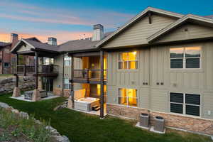 Multi-level exterior featuring balconies, a patio with a hot tub, and a rock retaining wall