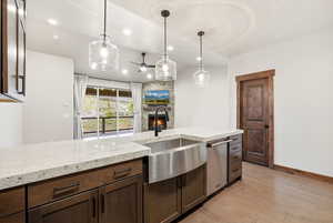 Kitchen island with a stainless steel farmhouse sink, white countertop, and dark wood-finish cabinetry