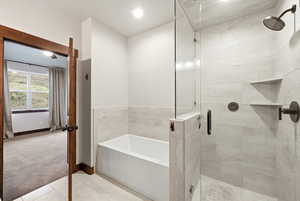 Contemporary bathroom featuring a deep soaking tub, glass-enclosed shower with tile surround, built-in shower shelving, and dark bronze fixtures