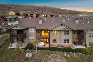 Multi-level residence featuring a neutral-toned exterior, multiple private balconies, a ground-level patio, and an outdoor hot tub