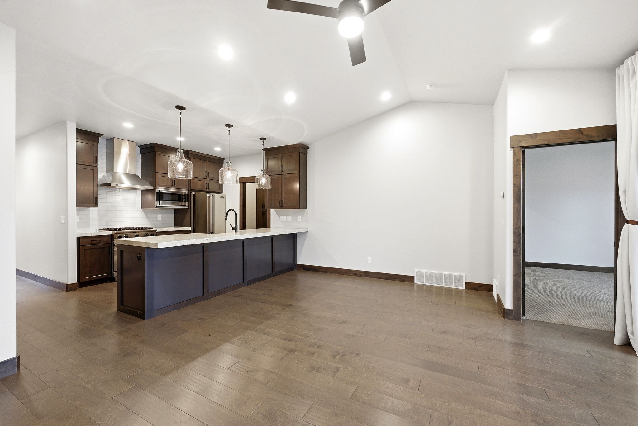 Open-concept kitchen and living area featuring wood-finish flooring, recessed lighting, and a ceiling fan
