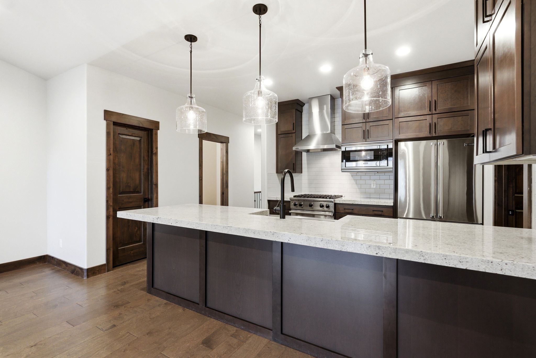 Kitchen island featuring a light-toned countertop, dark-toned cabinetry, and three pendant lights