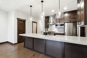 Kitchen island featuring a light-toned countertop, dark-toned cabinetry, and three pendant lights