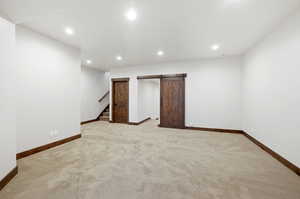 Spacious room featuring neutral carpet flooring, recessed lighting, and white walls