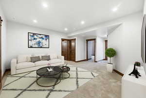 Spacious living area featuring recessed lighting, light-toned carpeting, white walls, and dark wood-finish trim and doors