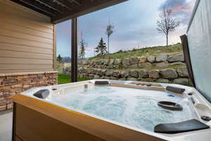 Bubbling outdoor spa on a concrete patio, featuring a stone retaining wall and a sloped grassy area