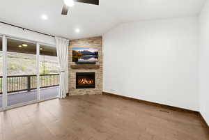 Living area featuring a stone-clad fireplace with a wood mantel, wood-finish flooring, and a ceiling fan