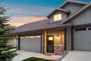 Contemporary exterior featuring board and batten siding, stone accents, and a dormer window