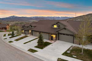 Townhome exterior featuring earth-toned siding, dark brown roofing, and stone accents