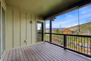 Covered deck featuring wood-finish flooring, vertical plank siding, and a black metal railing