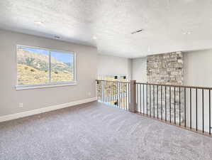 Carpeted loft area featuring a large window, recessed lighting, and a stacked stone accent wall