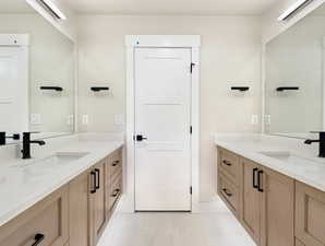 Dual vanity featuring light wood-finish cabinetry and white countertops