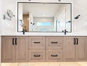 Dual vanity featuring light wood-finish cabinetry with black hardware, white solid surface countertops, and two undermount sinks with matte black faucets