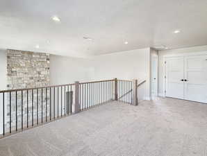 Expansive loft area featuring neutral carpeting, recessed ceiling lighting, and a stone accent wall