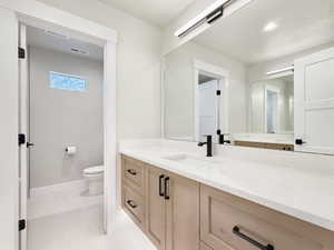 Bathroom vanity featuring light wood-finish cabinetry with matte black hardware, a light-colored speckled countertop, and an undermount sink with a black faucet