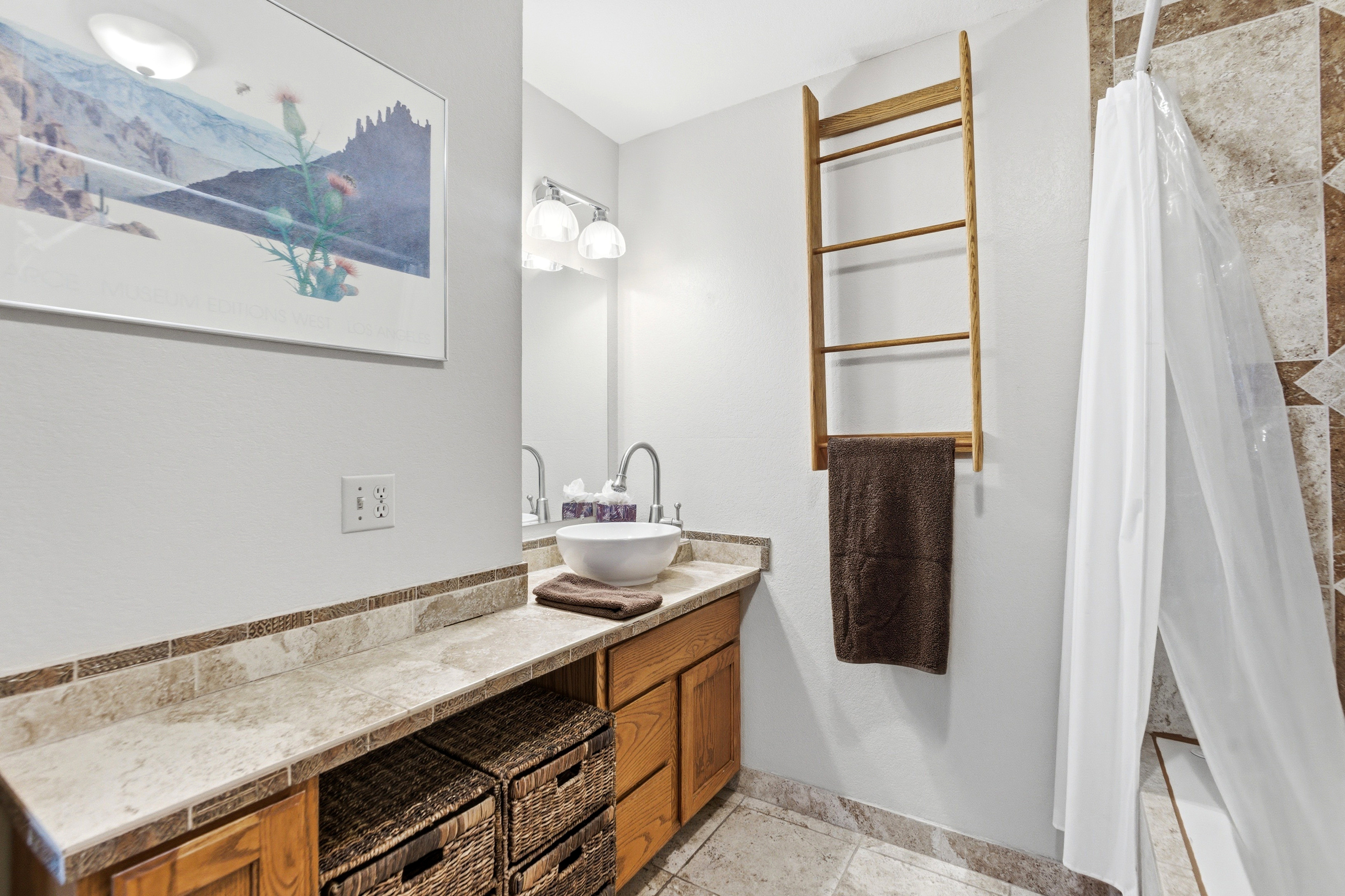 Bathroom vanity with a vessel sink, single-handle faucet, and overhead lighting