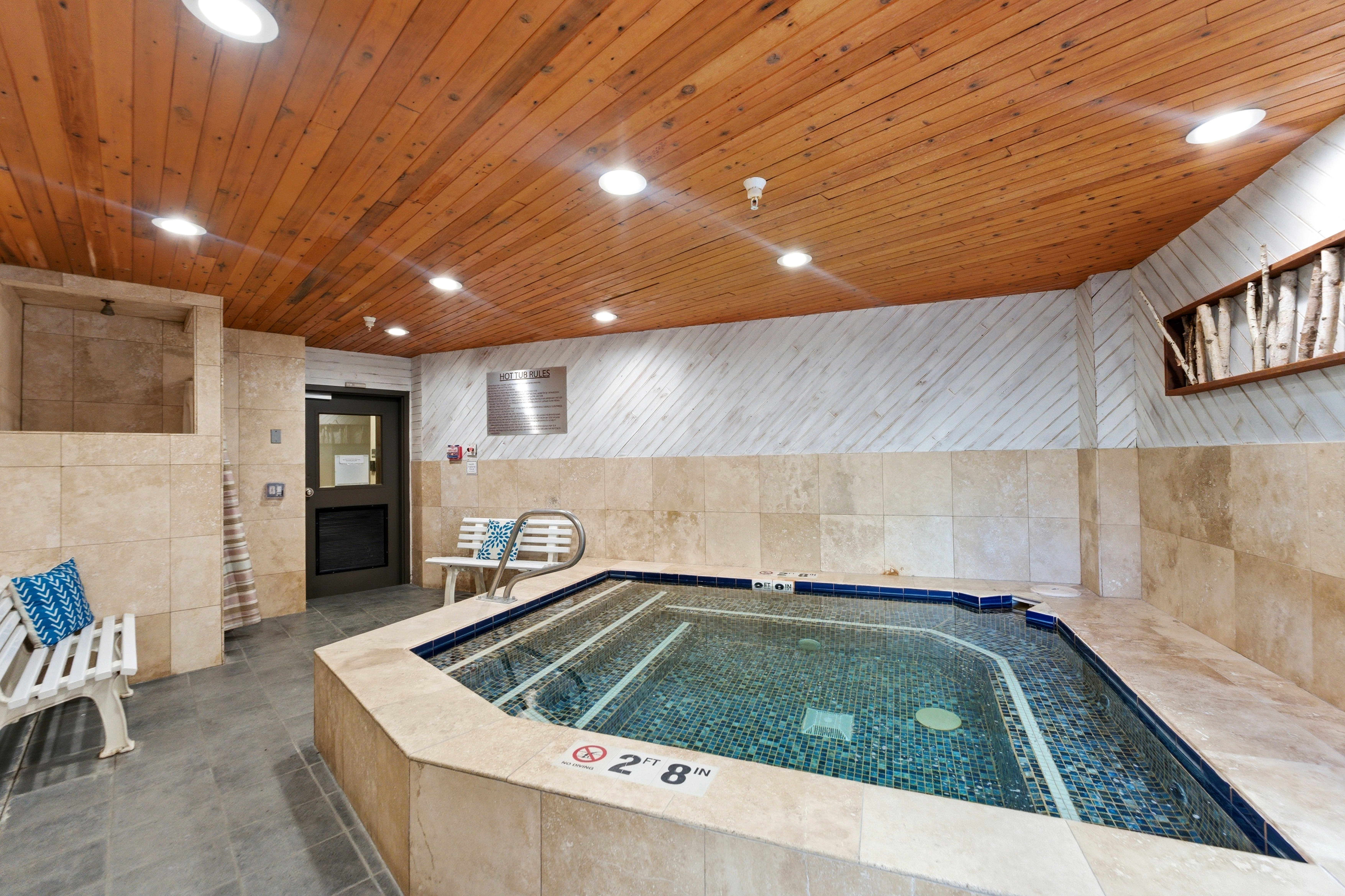 Indoor spa area featuring a tiled hot tub with perimeter grab rails
