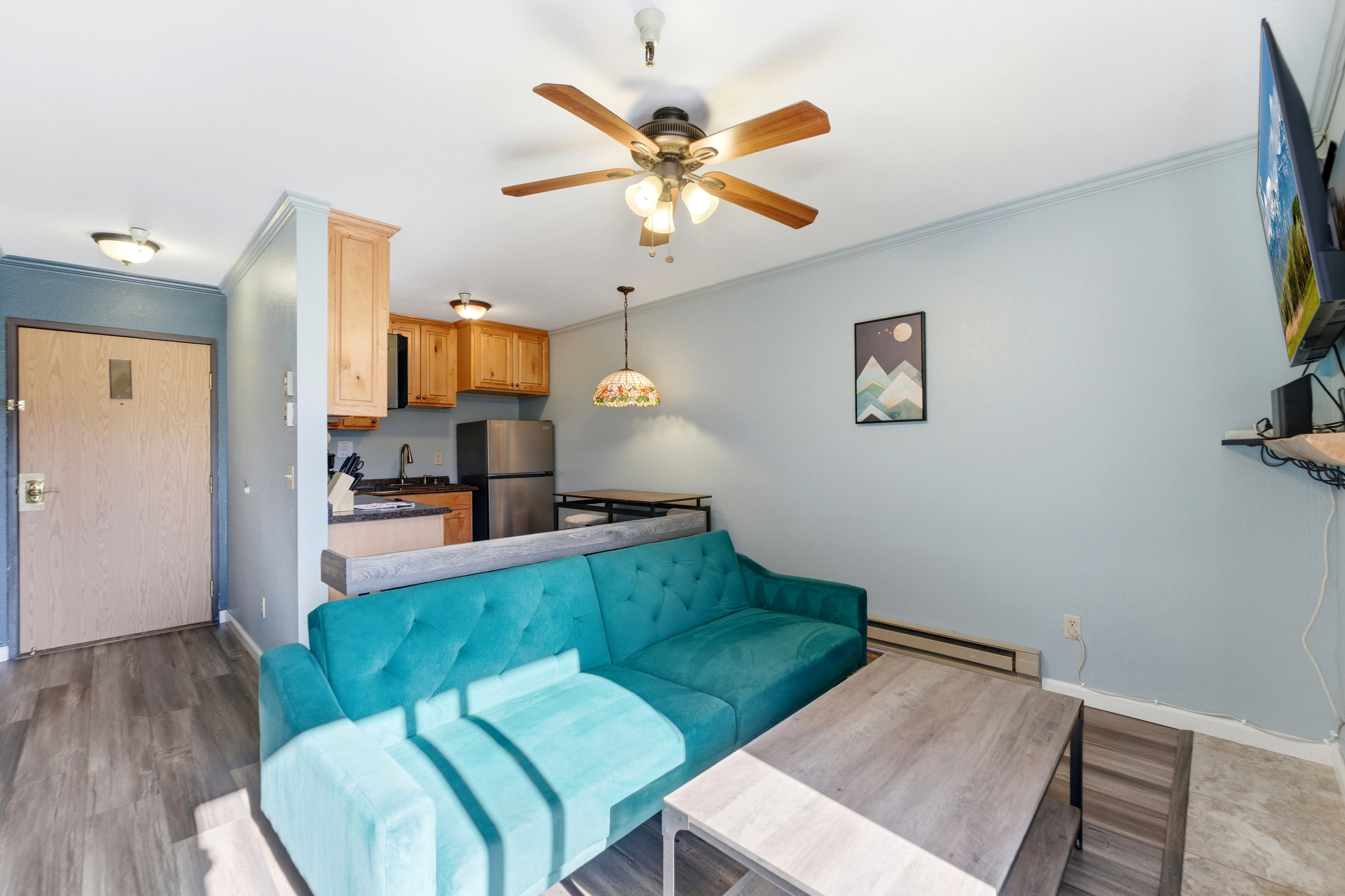 Open-concept living space featuring wood-finish flooring, a kitchen with light wood cabinetry, stainless steel appliances, a ceiling fan, and recessed lighting