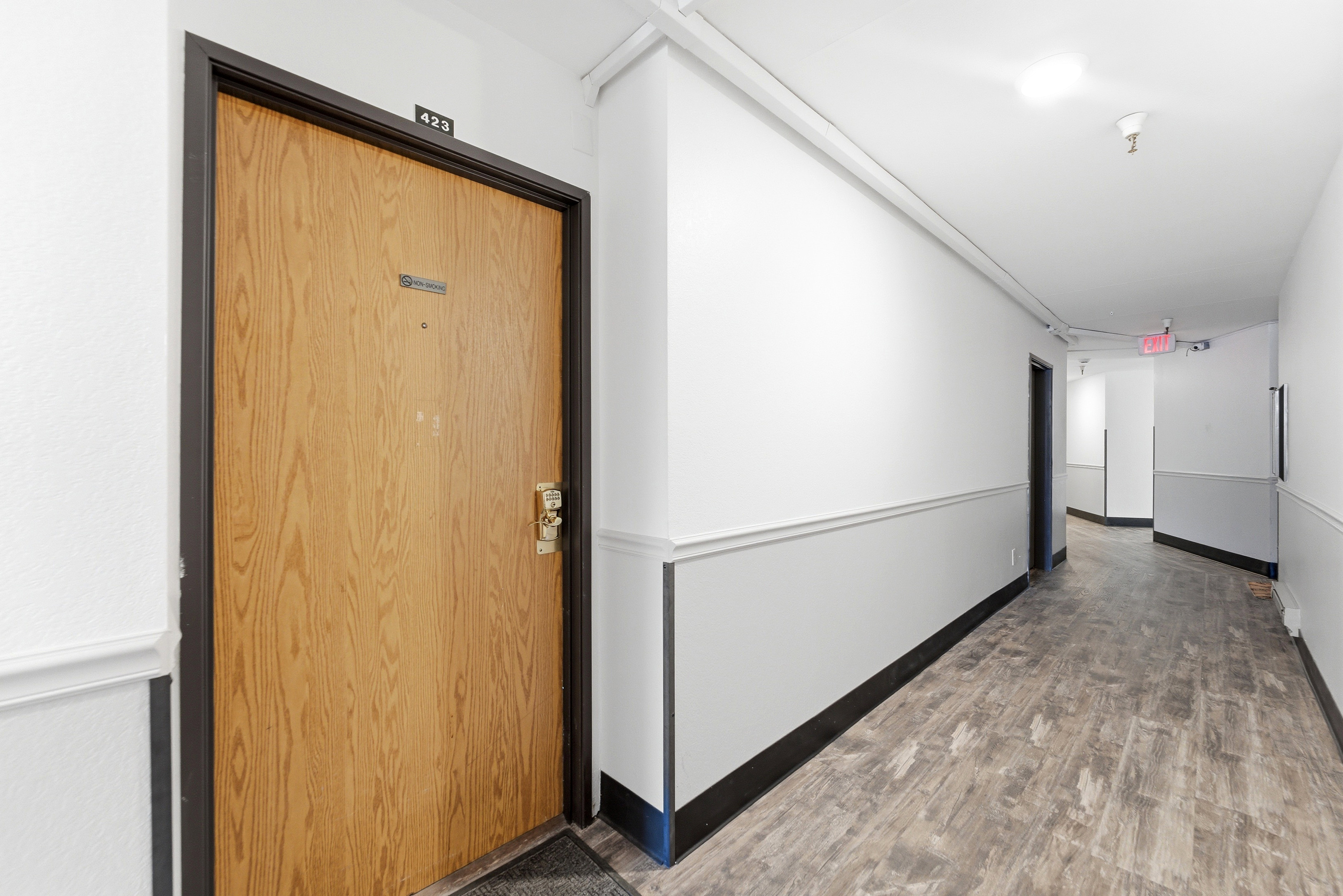 Entry door with wood-finish paneling, black trim, and brass-tone hardware