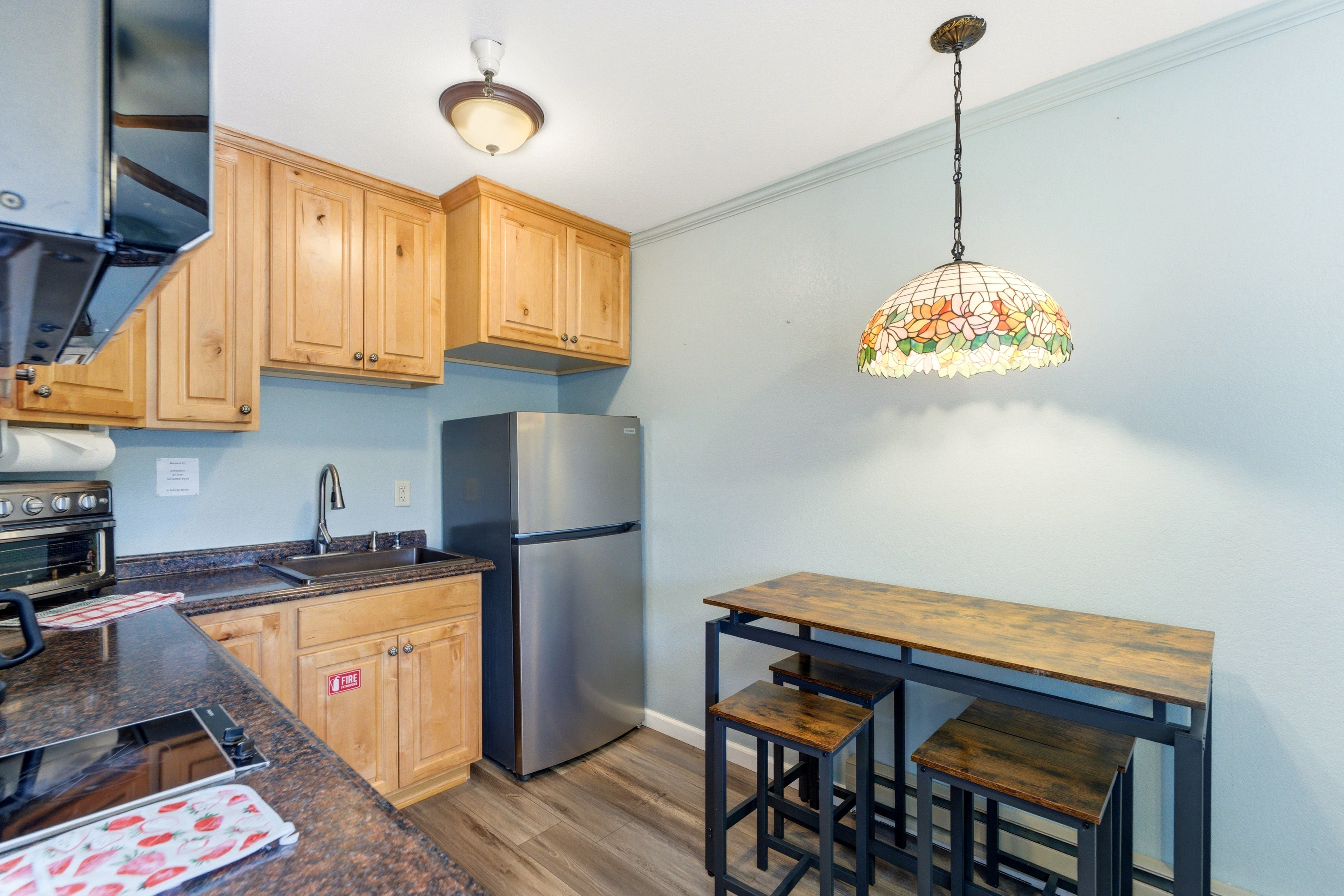 Kitchenette featuring wood-finish cabinetry, dark speckled countertops, and a stainless steel refrigerator